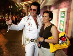 O imitador de Elvis Presley, Tom E. Lynd (à esquerda), posa para uma foto com a turista canadense Brenda Rediron na Strip, em 28 de junho de 2005, em Las Vegas, Nevada. Lynd é dono do Legends in Photos, um grupo de imitadores que se apresentam na Strip e posam com turistas em troca de gorjetas.