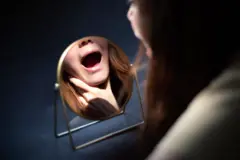 Mulher checando as amígdalas em espelho