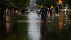 Homem7games baixar o esbicicleta7games baixar o esrua alagada, com a água na altura do joelho