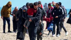 Abantu, bikekwa ko ari abimukira, bagenda ahitwa Dungeness mu Bwongereza, muri Kanama 2023