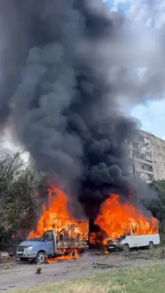 Запорожье: два горящих автомобиля на фоне дома, в который попала управляемая авиабомба.
