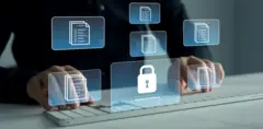 На заднем фоне человек в темной одежде сидит за стол, положив руки на белую клавиатуру. Над клавиатурой голограмы значков-файлов и замка с паролем.