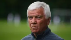 Володимир Мунтян у спортивній синій куртці на зеленомо тлі