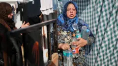 A Palestinian woman holds bottles filled with water