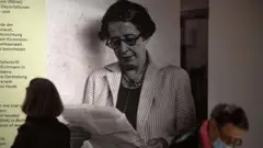 أحد الزوّار إلى جانب صورة للفيلسوفة والمنظّرة السياسية الألمانية-الأمريكية حنّة آرنت خلال العرض التمهيدي للصحافة لمعرض "حنّة آرنت والقرن العشرون" في المتحف التاريخي الألماني (DHM) في برلين في 6 مايو/أيار 2020
