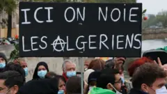 Pancarte disant : "Ici on noie les Algériens" vue lors d'une cérémonie de commémoration du 59e anniversaire du massacre de Paris en 1961 au pont Saint-Michel sur la Seine à Paris, France - 17 octobre 2020.