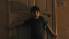 Cena de 'A Hora do Mal' mostra um menino assustado atrás de uma porta