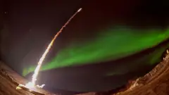 Lanzamiento de un misil nocturno con aurora polar en una imagen de la NASA.