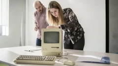 Duas pessoas pertojogo brabetcomputador Macintosh antigo