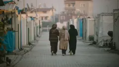 Konteynerların arasından yürüyen üç kadın. 