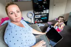 Middle Aged Women working from home in office whilst also looking after her young daugther.