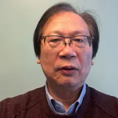 O professor Shun Au, olhando de frente para a câmera, com camisa de colarinho e óculos