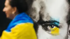 德國杜塞爾多夫一位身披烏克蘭國旗的女示威者站在Anna Movenko油畫作品前（29/10/2022）