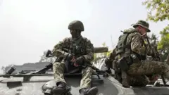 Ifoto yatanzwe na serivisi yo gutangaza amakuru yo muri minisiteri y’ingabo z’Uburusiya, ku itariki ya 9 Nzeri (9) mu 2022, igaragaza abasirikare b’Uburusiya bari mu modoka itamenwa n’amasasu asanzwe, bari ahantu hatatangajwe.