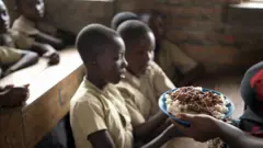 Umutetsi arimo guhereza ibiryo abanyeshure 