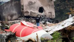 Um bombeiro fica ao lado dos destroços do Boeing 787-8 Dreamliner da Air India