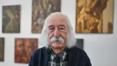 Іван Марчук у картатій сорочці та синьому светрі дивиться прямо 