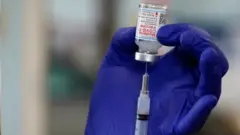 Mão com luva prepara dose de vacina