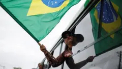A man holds a Brazilian flag from the window of a bus as he is detained after Congress was stormed by Bolsonaro supporters