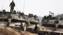 Tanques de artilharia posicionados com diversos soldados e bandeira de Israel