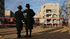 আরাদ শহরে ক্ষতিগ্রস্ত ভবন দেখছেন দুইজন ইসরায়েলি