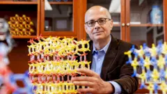 Omar Yaghi sentado con unas estructuras moleculares de colores.
