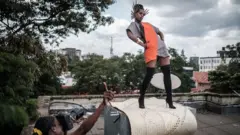La photographe et directrice artistique kenyane Barbara Minishi (G) prend des photos de sa colocataire et styliste de mode Wambui Thimba (D)