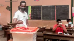 Un électeur dépose son bulletin de vote dans un bureau de vote d'une école primaire de Cotonou, le 17 mai 2020, à l'occasion des élections locales au Bénin.
