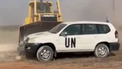 Bir buldozer BM aracını yoldan itiyor 