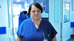 La Dra. Oana Goidescu, cirujana, trabajaba de turno en el hospital de Buzău, vestida de azul. Tiene el pelo negro de longitud media.