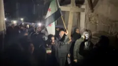 در محله باب توما در دمشق، معترضان با صلیب و پرچم‌های سوریه راهپیمایی کردند و شعار «جان خود را برای صلیب‌مان فدا می‌کنیم» سر دادند.