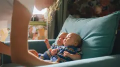 Dos bebés gemelos son observados por una mujer. 