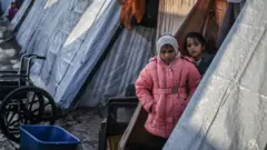 Palestinian children stand by the tents housing them in Rafah, southern Gaza Strip. Photo: February 2024