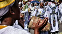 ክብረ በዓል ላይ የኦርቶዶክስ ቤተ ክርስቲያን ዘማሪያንን ልብስ የለበሰች ሴት ከበሮ እየመታች