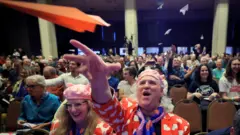 Люди из зала кидают самолетики