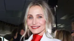 Cameron Diaz, com blusa vermelha sob terno branco