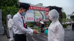 장철구평양상업대학의 한 학생이 캠퍼스에 들어가기전에 손에 손 소독제를 받는 모습