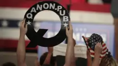 QAnon supporter holds up poster at Trump rally