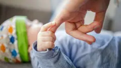 طفل رضيع يُمسك بخنصر شخص كبير