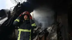 Пожарный на фоне почерневших развалин