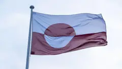 Гренландский флаг Erfalasorput развевается перед зданием представительства Гренландии в Нордатлантенс Брюгге в Копенгагене, Дания, 9 января 2026 года. Он красно-белый, с красно-белой окружностью в центре