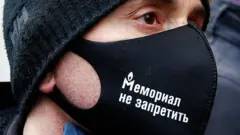 Человек в маске с надписью "Мемориал не запретить"