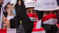 Mwanamke wa Iraqi anaandamana akiwa amevalia kofia ya ya ujenzi iliyoandikwa neno "#Amani" kwa lugha ya kiarabu wakati wa maandamano dhidi ya serikali katika mji wa Basra, kusini mwa Iraq Novemba 29, 2019.