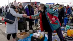 Una voluntaria ofrece algo de comida a una ucraniana en la frontera entre Ucrania y Polonia.