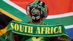 A woman wears South African football colours and the national flag.
