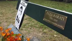 نیمکتی در پارک منسفیلد ولینگتون با پلاکی به یاد رضا براتی، پناهجوی کرد ایرانی که در خشونت‌های اردوگاه مانوس کشته شد