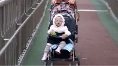 A woman pushes a baby carriage on an overpass in Beijing.