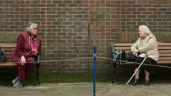 Two women observe social distancing measures in York