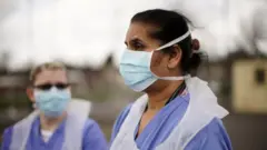 NHS nurses speak to the media as they wait for the next patient at a drive through Coronavirus testing site on March 12, 2020
