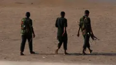 Armed men walk in Khartoum on Monday